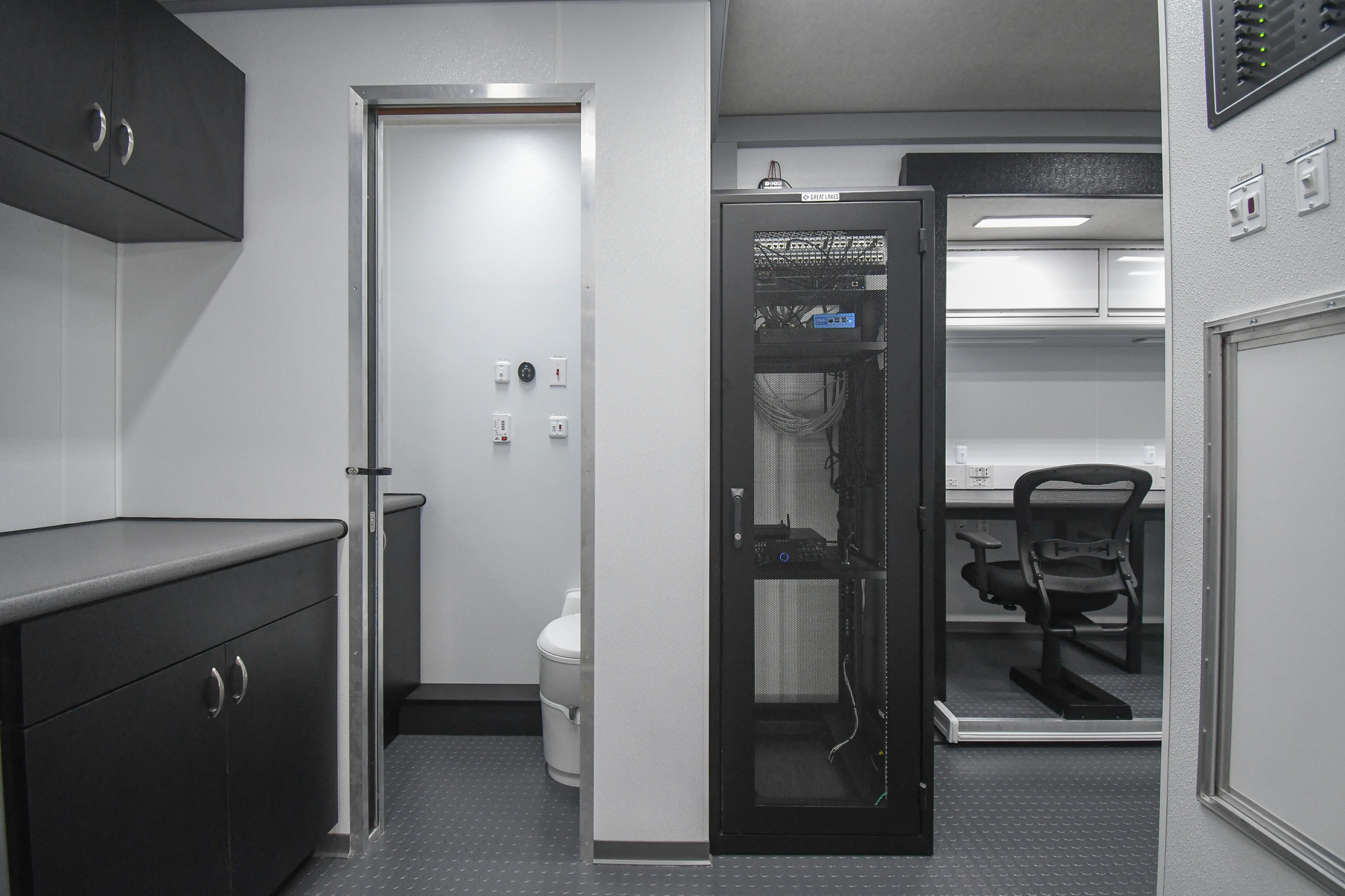 A partial view of the kitchenette, restroom, electronics rack, and workstation inside the unit for Kinston, NC.